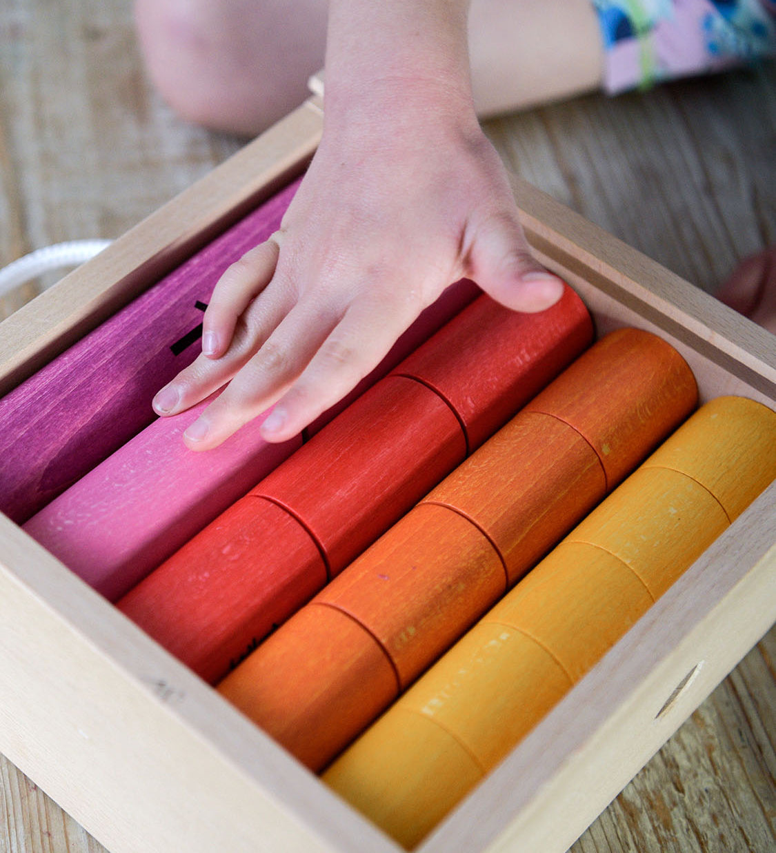 Bajo Fraction Set Maths Resource Learning Toy showing child's hand over the fraction blocks in a wooden box