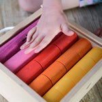 Bajo Fraction Set Maths Resource Learning Toy showing child's hand over the fraction blocks in a wooden box