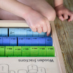 Bajo Fraction Set Maths Resource Learning Toy showing child's hand picking the fraction blocks from inside the wooden fractions box