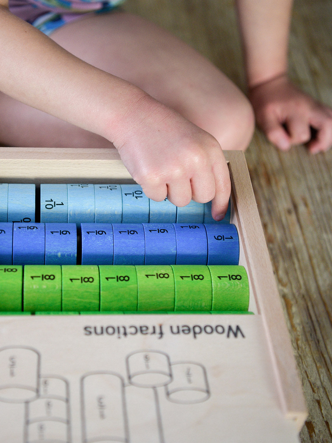 Bajo Fraction Set Maths Resource Learning Toy showing child's hand picking the fraction blocks from inside the wooden fractions box