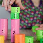 Bajo Fraction Set Maths Resource Learning Toy showing child's hand playing with the fraction blocks on a wooden table
