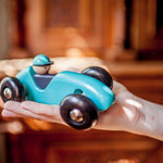 Bajo Wooden Toy Steering Racing Car - Blue in an adult hand for scale