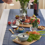 Bambu medium and large bamboo cutting and serving boards on a blue table cloth in a party setting with various food items on top for scale