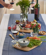 Bambu medium and large bamboo cutting and serving boards on a blue table cloth in a party setting with various food items on top for scale