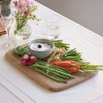 Close up view of the large Bumbu bamboo serving and cutting board on a white table cloth with various foods on top and showing the bamboo detail