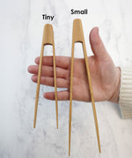 The Bambu Tiny and small Tongs shown on a person's hand. 