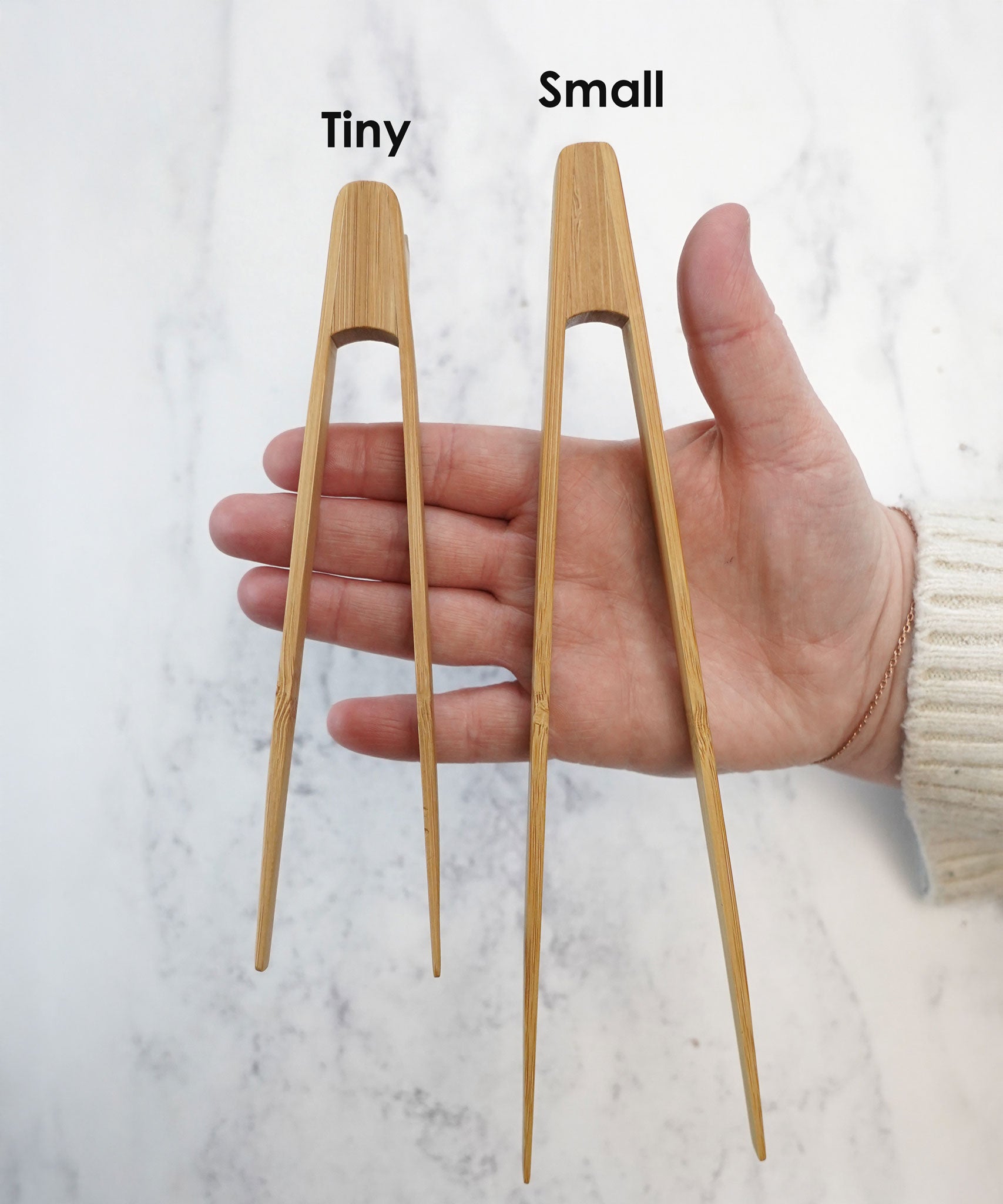 The Bambu Tiny and small Tongs shown on a person's hand. 