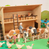 Beck Holzspielzeug large wooden farm barn filled with Ostheimer wooden farm animal and people figures in an imaginative small-world play scene.