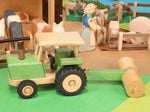 Beck Holzspielzeug traditional wooden toy tractor pulling farm roller attachment in small-world play scene with Ostheimer animal figures.