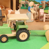 Beck Holzspielzeug traditional wooden toy tractor pulling farm roller attachment in small-world play scene with Ostheimer animal figures.