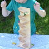 A child playing with the Beck Toys Beechwood Cascading ‘Tower Running Track’ with Race Cars. The child has placed the green coloured race car on the track and has his hands held up in anticipation whilst he watches the car zoom down the track.