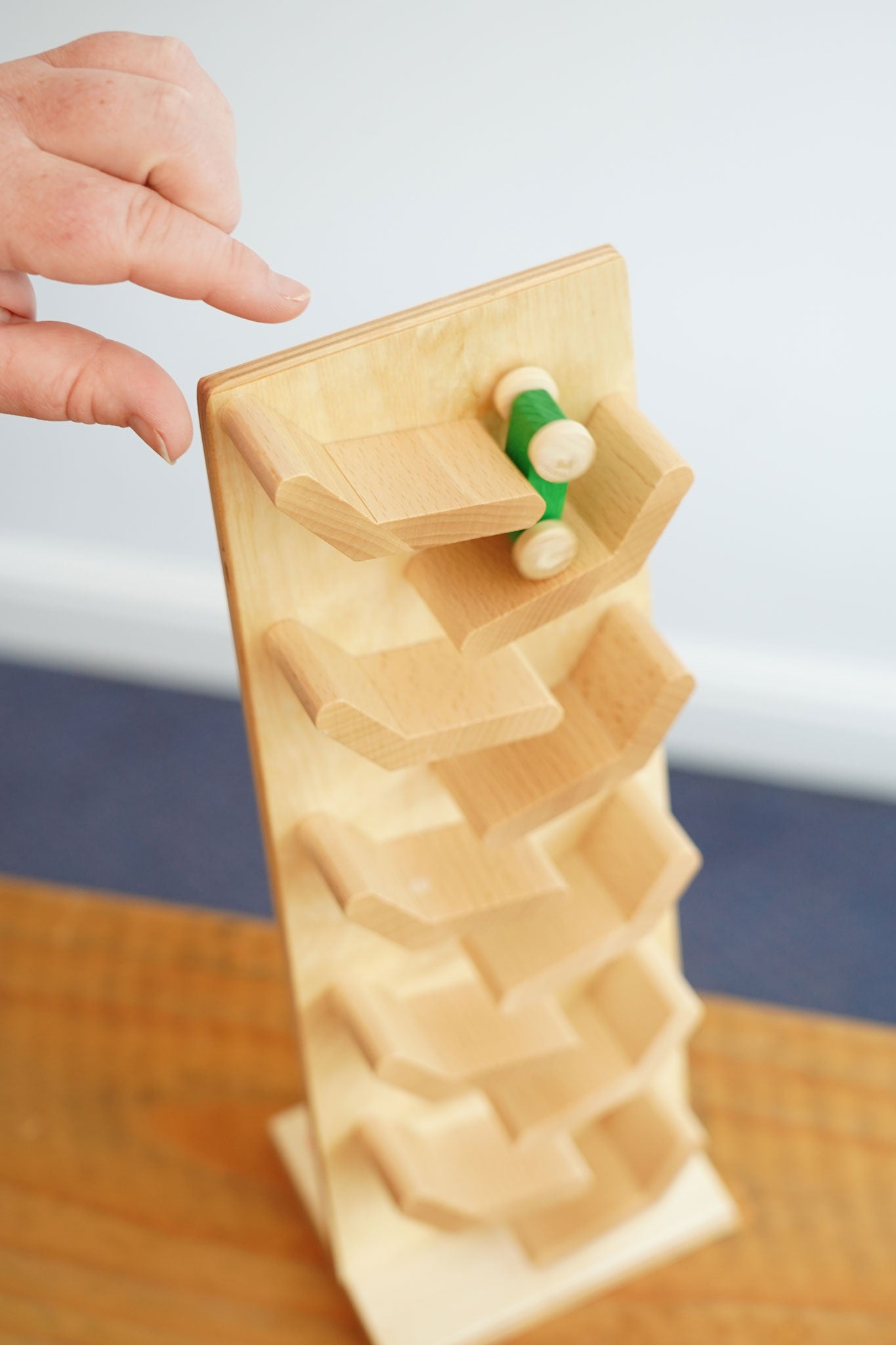 A view from above of a green coloured racing car being placed onto the Beck Toys Cascading Tower Run Track .