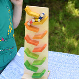 A child playing with the Beck Toys Beechwood Cascading ‘Tower Running Track’ with Millipede Car Train. The car train can be seen racing down the track and a child is watching on in anticipation. 