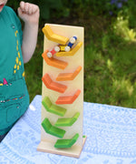 A child playing with the Beck Toys Beechwood Cascading ‘Tower Running Track’ with Millipede Car Train. The car train can be seen racing down the track and a child is watching on in anticipation. 