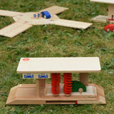 Beck wooden toy car wash placed on grass outdoors with other Beck toys in the background.
