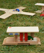 Beck wooden toy car wash placed on grass outdoors with other Beck toys in the background.