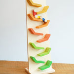 The Beck Toys Beechwood Cascading Tower Running Track with colourful Millipede Car Train placed on a wooden surface. The car train is blurred in motion as it races down teh track.