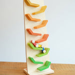 The Beck Toys Beechwood Cascading Tower Running Track with colourful Millipede Car Train placed on a wooden surface. The car train is blurred in motion as it races down teh track.