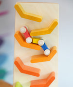 A close up of the millipede car train on the Beck Toys Beechwood Cascading Tower Running Track. Motion blue can be seen on the wooden car train as it races down the track.
