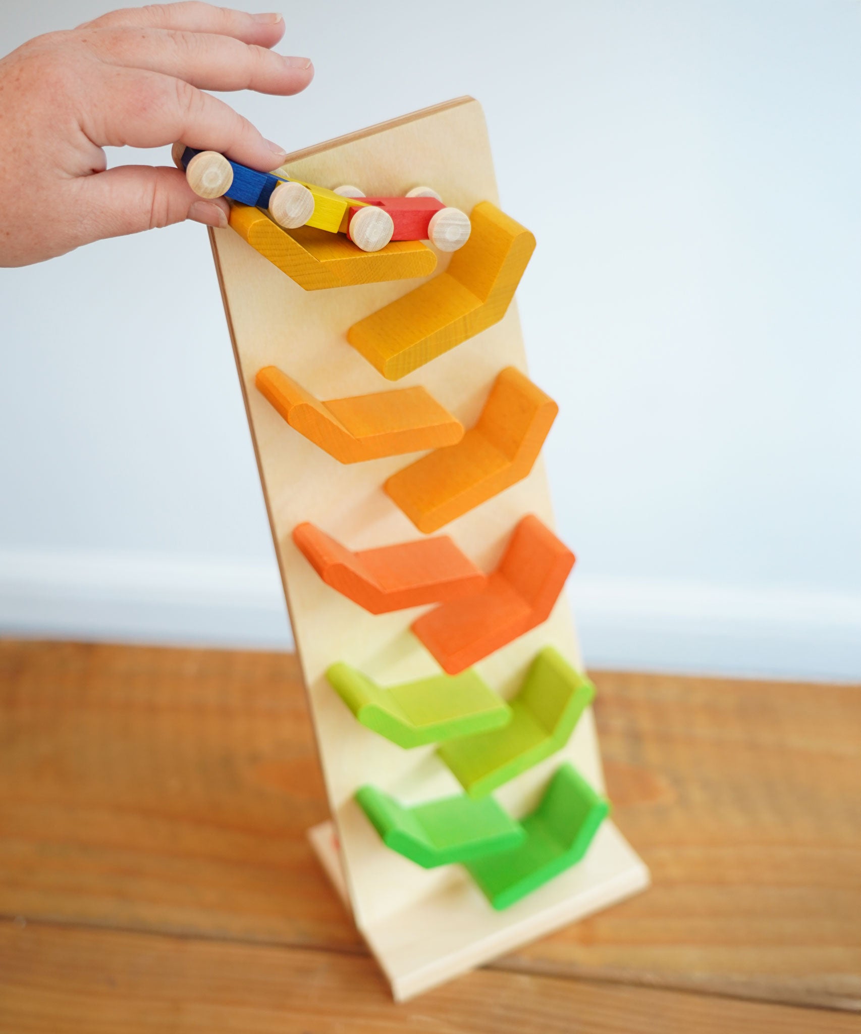 The wooden millipede car train being placed on the Beck Toys Beechwood Cascading Tower Running Track.