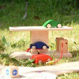 Beck wooden garage & petrol station placed on grass outdoors in front of the roundabout set with wooden cars.