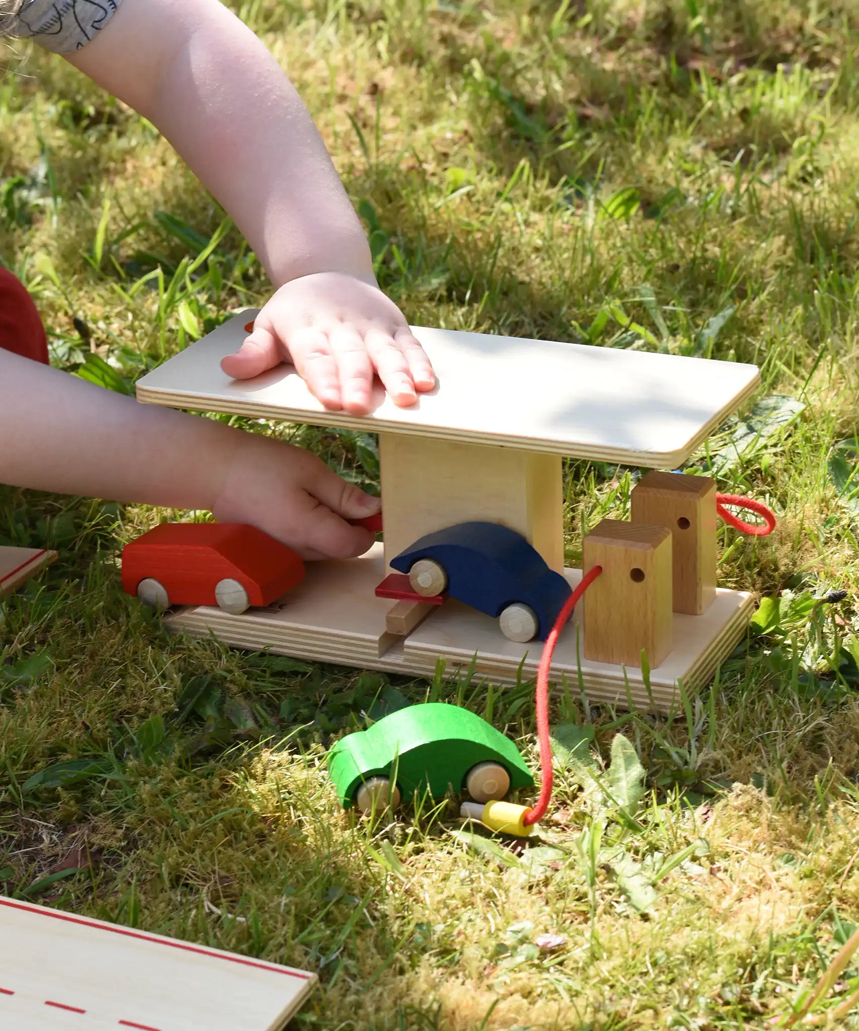 Child lifting the ramp on the Beck wooden garage & petrol station using the red handle.