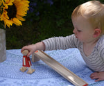 A young child reaching for the wooden walking figure from the Beck Toys Nurmi Ramp Walker Wooden Toy.