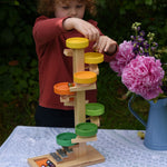 A child placing glass marbles on the top of the Beck Toys Beech Wood Plate Tower Marble Run with Glockenspiel.
