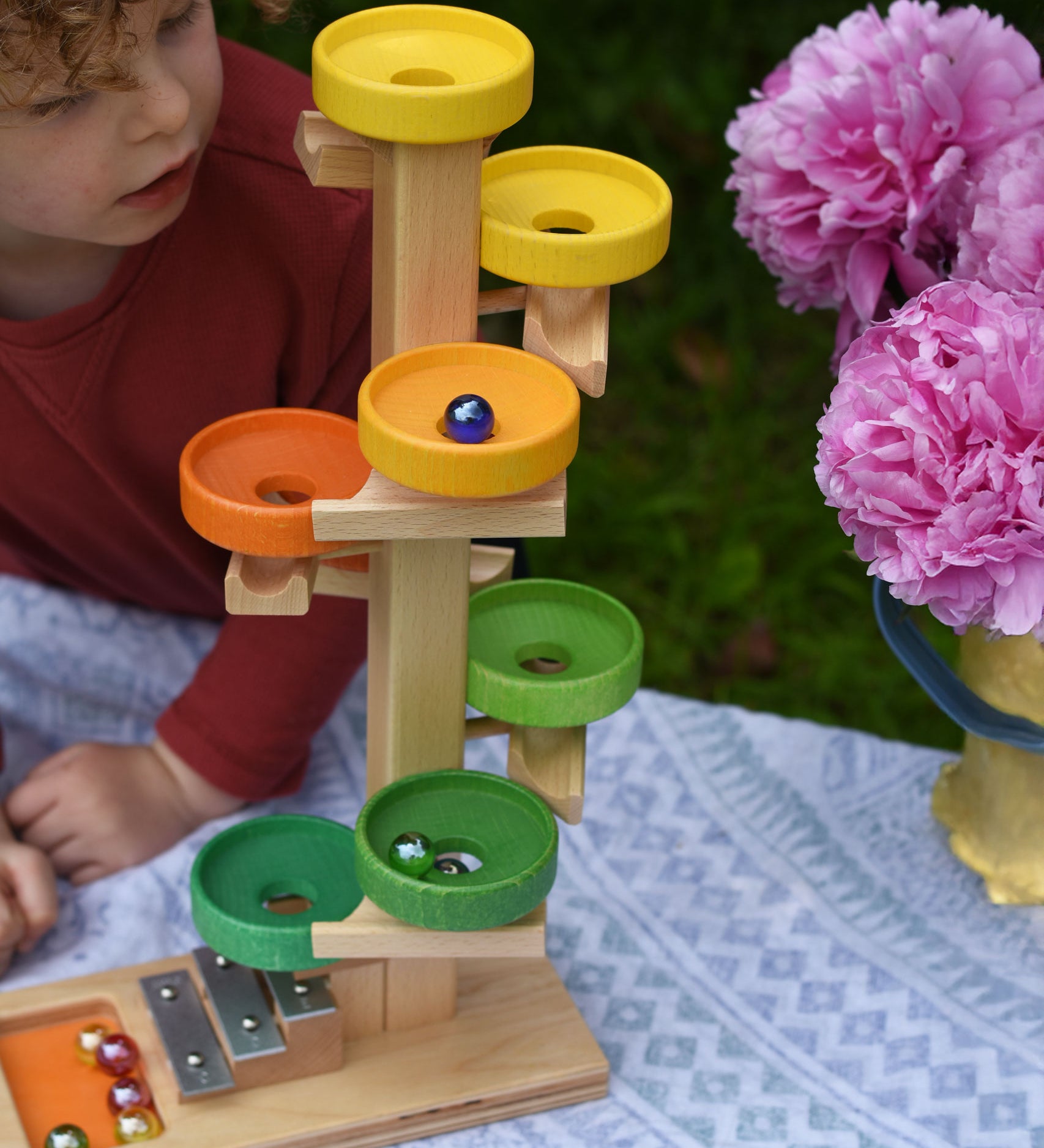 A child observing the glass marbles twirling down the Beck Toys Beech Wood Plate Tower Marble Run with Glockenspiel. 