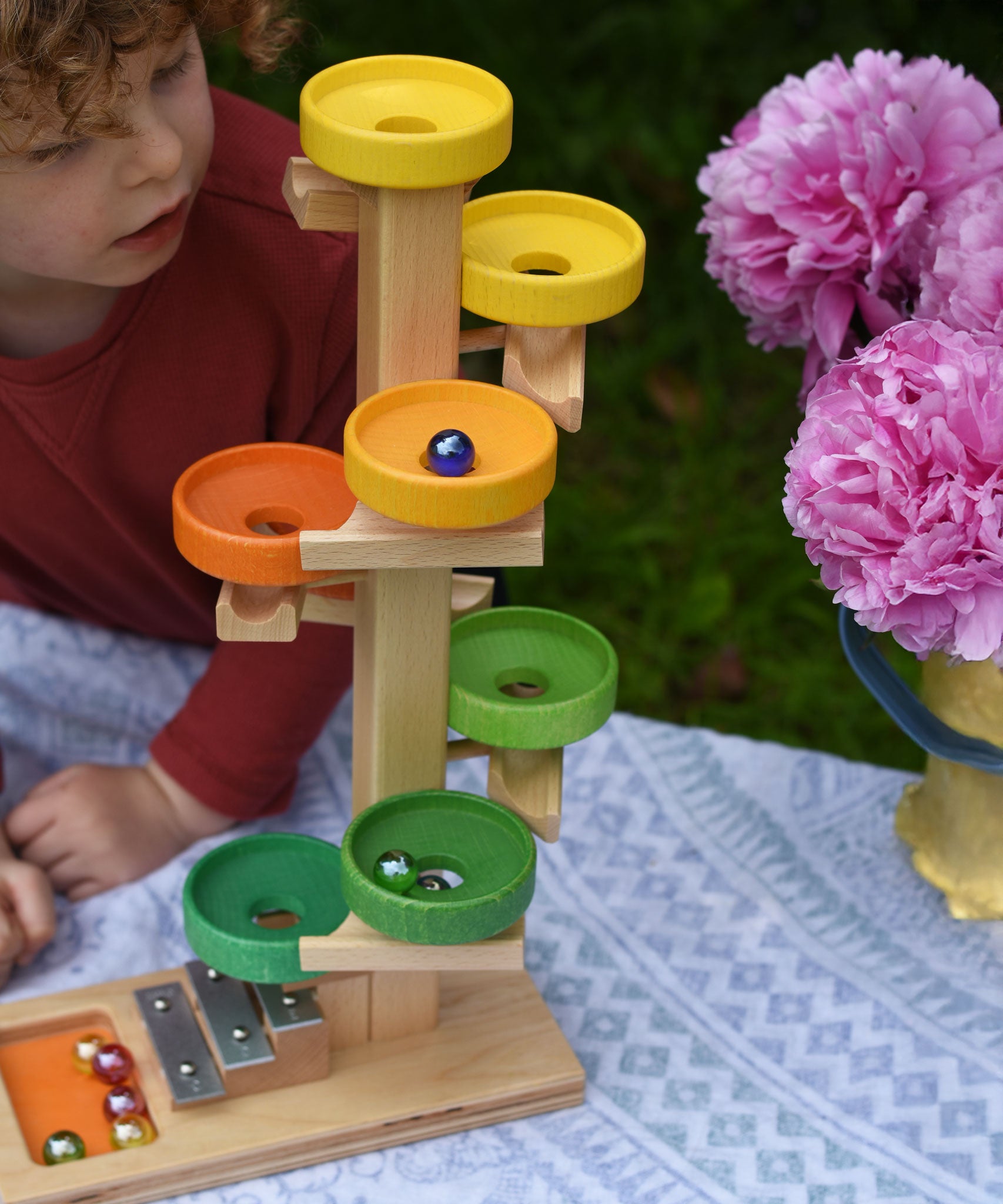 A child observing the glass marbles twirling down the Beck Toys Beech Wood Plate Tower Marble Run with Glockenspiel. 