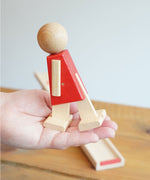 The red colour body walking figure from the Beck Toys Nurmi Ramp Walker Wooden Toy set in an adult's hand.