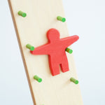 A close up of the red figure on the Beck wooden Toys Wobbler. The red figure is blurred in motion as it descends down the wobbler.