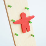 A close up of the red figure on the Beck wooden Toys Wobbler. The red figure is blurred in motion as it descends down the wobbler.