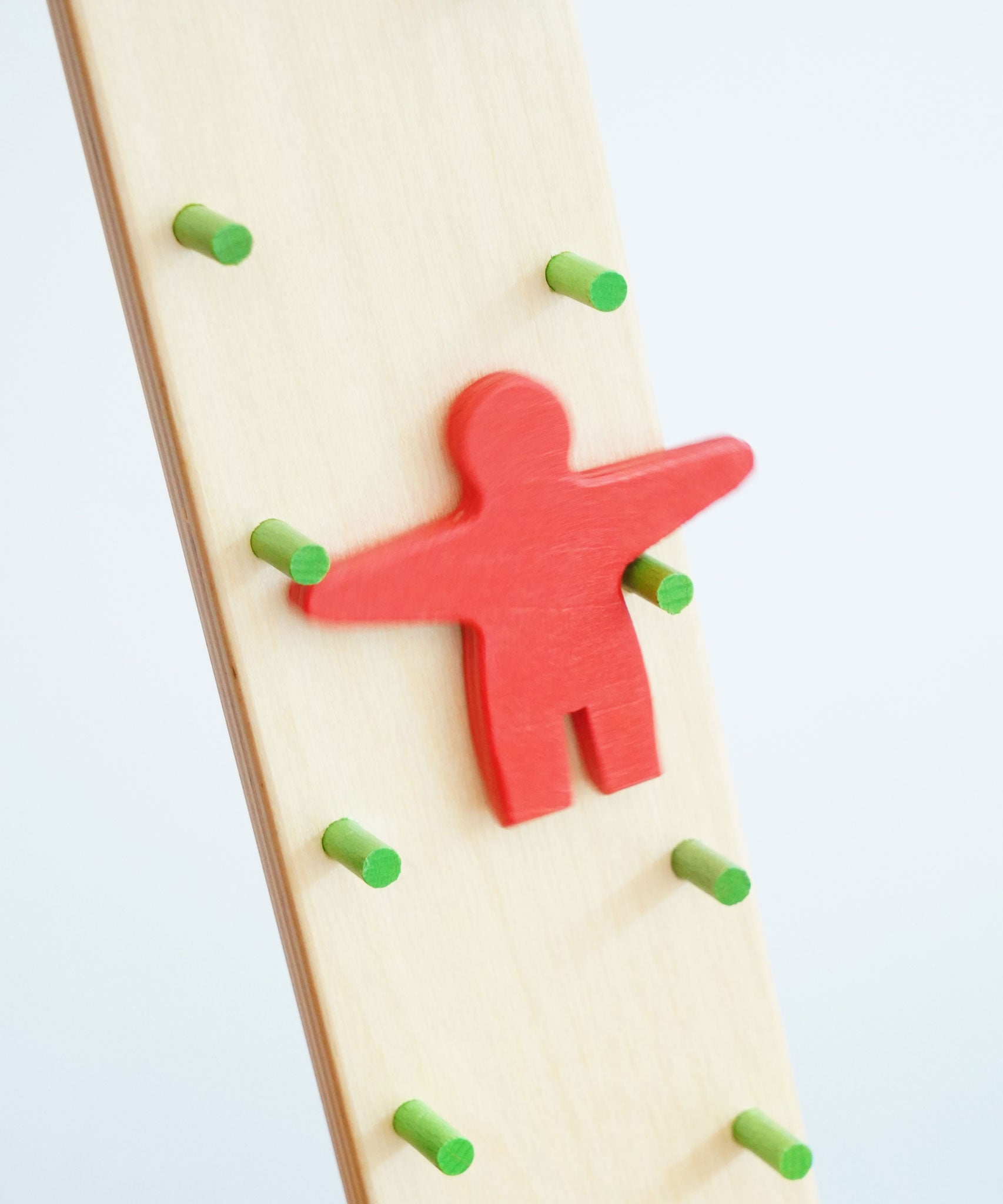 A close up of the red figure on the Beck wooden Toys Wobbler. The red figure is blurred in motion as it descends down the wobbler.