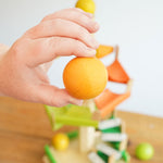 A close up of a wooden ball from the Beck Toys Beechwood Step Tower with Glockenspiel Chimes in an adult's hand. 