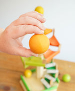 A close up of a wooden ball from the Beck Toys Beechwood Step Tower with Glockenspiel Chimes in an adult's hand. 