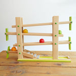The Beck Toys Beechwood Ball Run ‘Roller Coaster Ramp’ with Glockenspiel Chimes placed on a wooden surface. The four wooden coloured balls have been set in motion on the track 