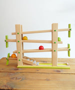 The Beck Toys Beechwood Ball Run ‘Roller Coaster Ramp’ with Glockenspiel Chimes placed on a wooden surface. The four wooden coloured balls have been set in motion on the track 