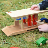 Beck wooden toy car wash being played with by a child on grass outdoors.