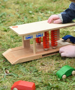 Beck wooden toy car wash being played with by a child on grass outdoors.
