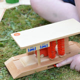 Beck wooden toy car wash being played with by a child, pushing the slider to make the red brushed rotate.