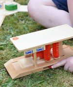 Beck wooden toy car wash being played with by a child, pushing the slider to make the red brushed rotate.