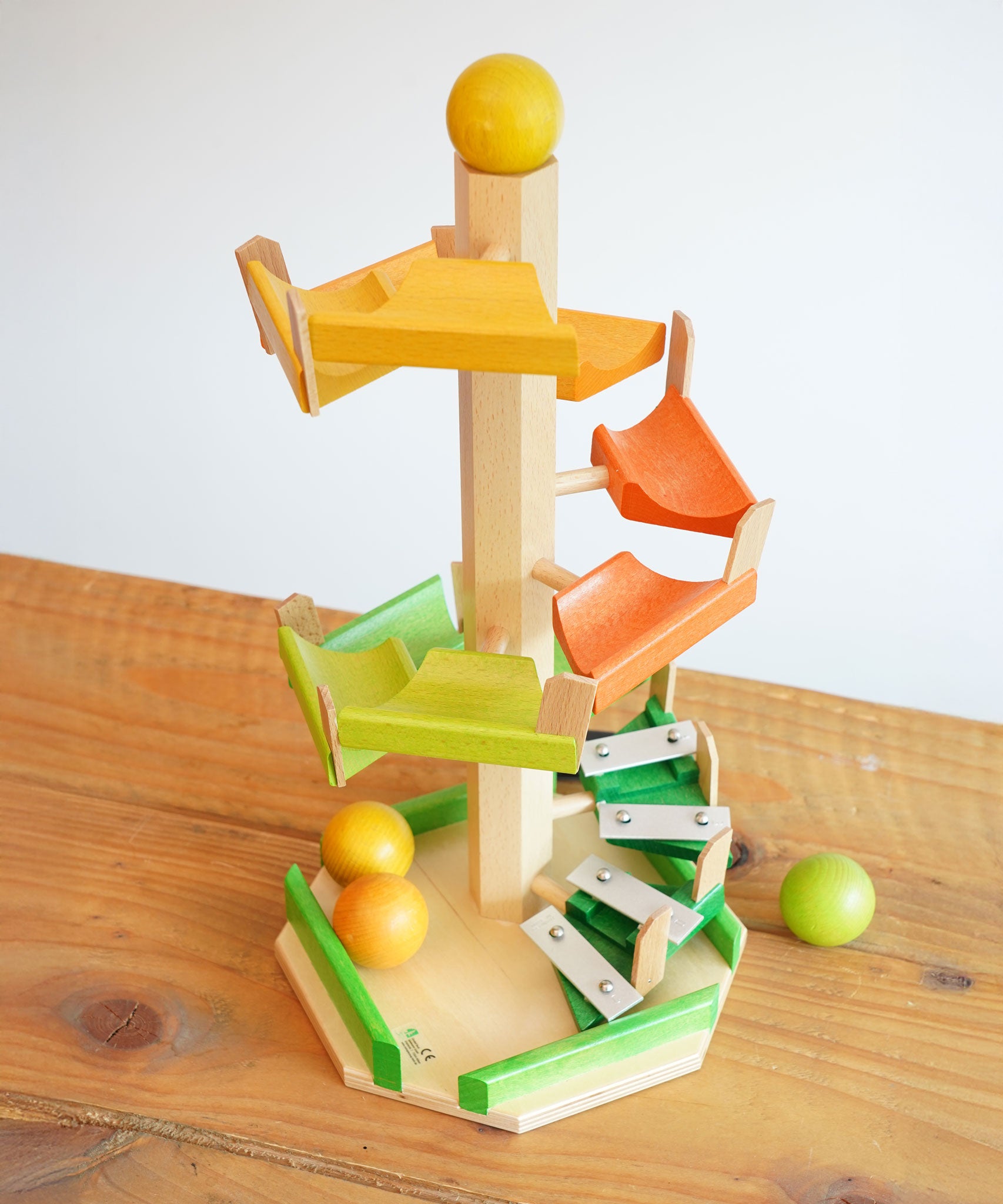 The Beck Toys Beechwood Step Tower with Glockenspiel Chimes placed on a wooden surface. The set comes with the coloured wooden balls.