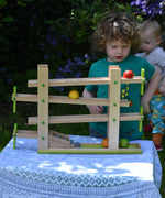 A child playing with the Beck Ball Run Musical Track which as been placed on a small table outdoors. 