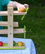A close up of a child's hand placing a yellow coloured wooden ball on the Beck Ball Run Musical Track.