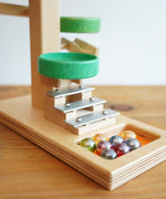 A close up of the glass marbles placed on the base of the Beck Toys Beech Wood Marble Run ‘Plate Tower’ with Glockenspiel.