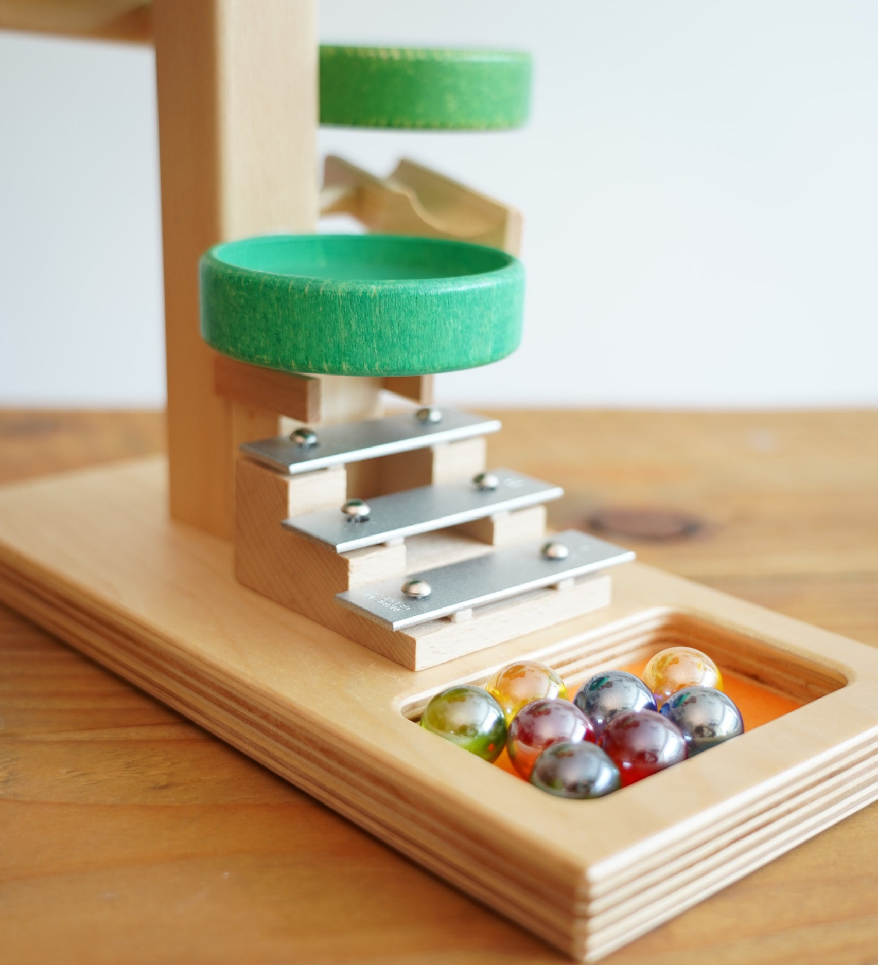 A close up of the glass marbles placed on the base of the Beck Toys Beech Wood Marble Run ‘Plate Tower’ with Glockenspiel.
