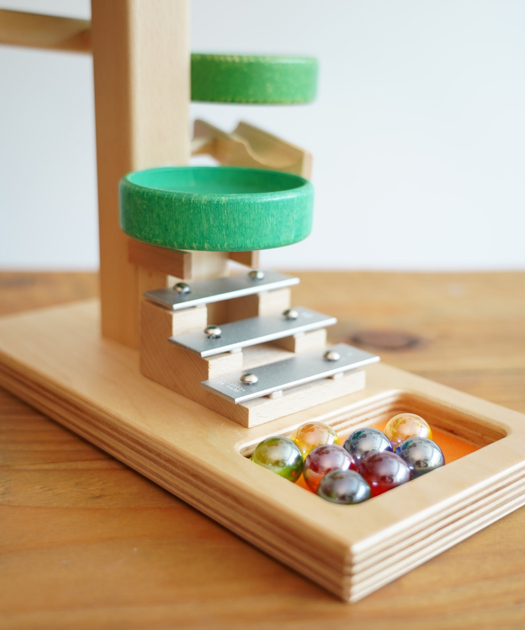 A close up of the glass marbles placed on the base of the Beck Toys Beech Wood Marble Run ‘Plate Tower’ with Glockenspiel.