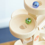 A close up of glass marbles, blurred in motion whilst they cascade down the Beck Toys Maple Wood Marble Run Plate Tower.