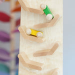 A close up of the yellow and green coloured wooden racing cars racing down the Beck Toys Cascading Tower Race Track. The cars are slightly blurred in motion. 